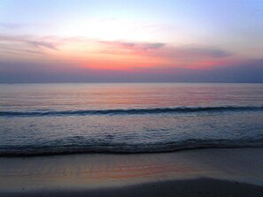Una playa con olas y un atardecer.