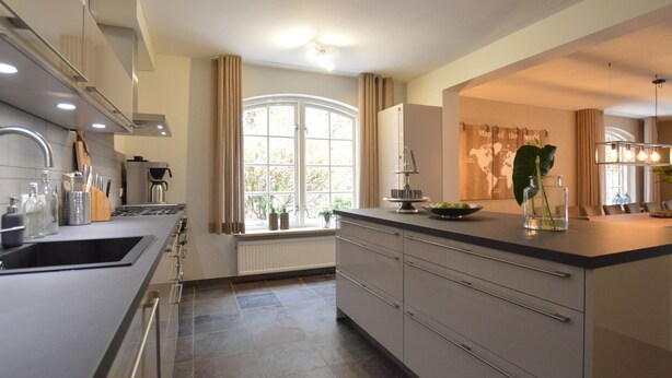 A modern kitchen with a large island, stainless steel appliances, and a view of the outdoors. - Spacious Villa Near Arcen in a Wooded Area (Arcen)