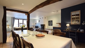 A dining area with a table set for four, wooden chairs, a fireplace, and a view of the outdoors.