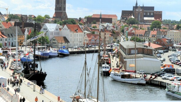 Ein Hafen mit Booten, einem Glockenturm und historischen Gebäuden.