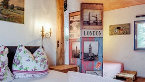 Ein Schlafzimmer mit einem Bett, Kissen, einem Nachttisch, einer Wandlampe und einem Poster von New York und London.