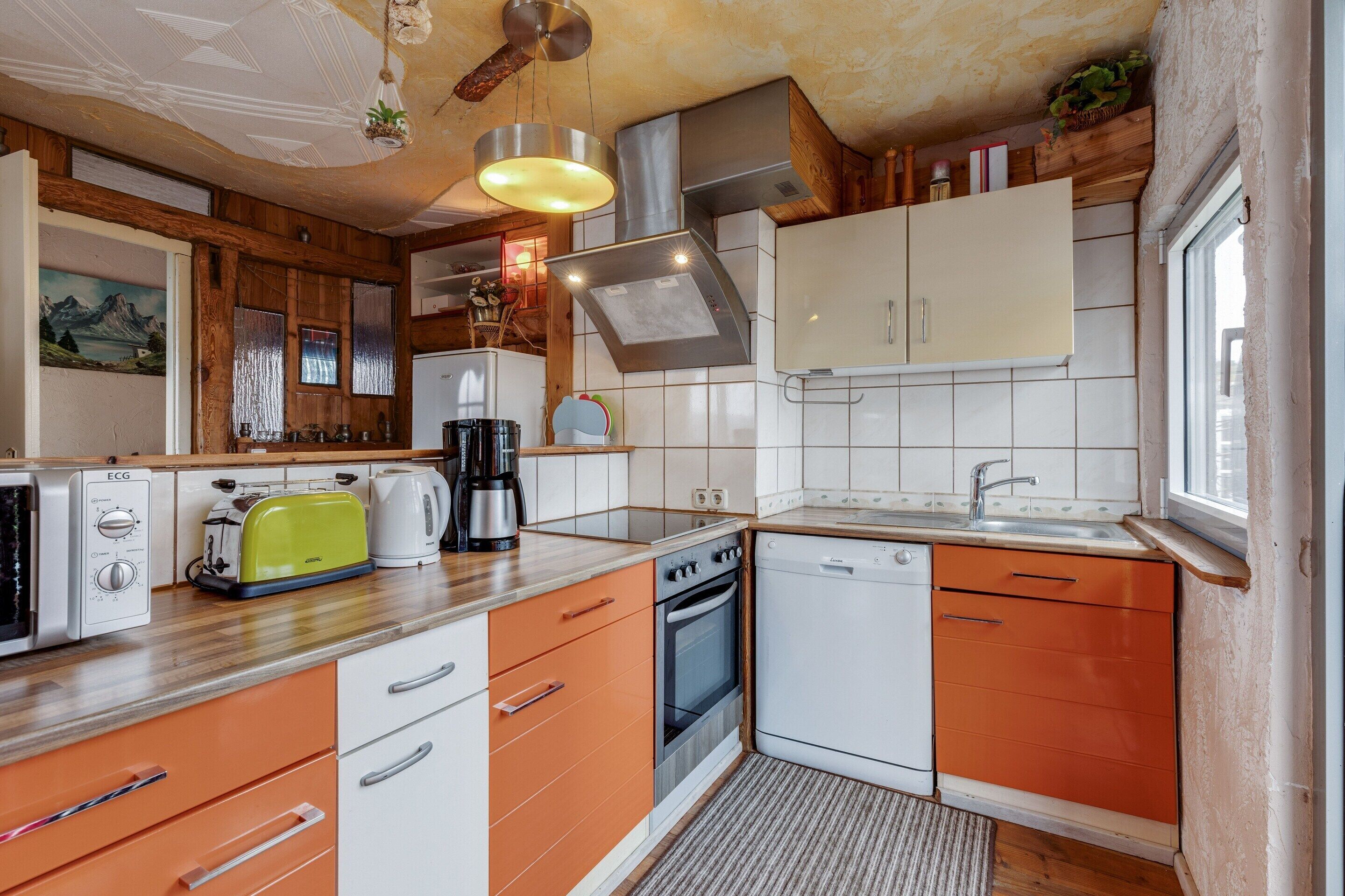 A compact kitchen with a toaster, coffee maker, oven, and dishwasher.