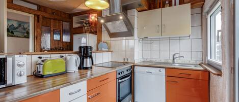A compact kitchen with a toaster, coffee maker, oven, and dishwasher.