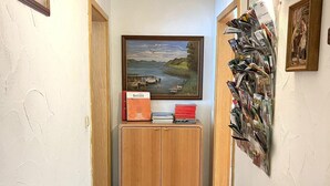 Um corredor com um armário de madeira, um quadro de paisagem emoldurado e um álbum de fotografias fixado na parede.