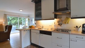 Une cuisine moderne avec des meubles blancs, une cuisinière à gaz et une grande fenêtre.