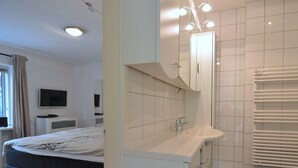 Une chambre d’hôtel moderne équipée d’un lit, d’une télévision, d’une salle de bain avec un lavabo et une douche.