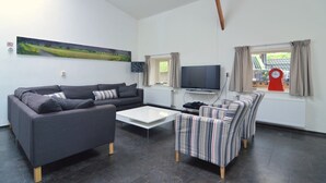 A living room with a sofa, armchairs, a coffee table, a flat-screen TV, and a window with curtains. - Holiday Home in Olst-wijhe With Sauna (Olst)