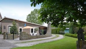 A building with a stone facade, a covered outdoor seating area, and a statue in the foreground. - Holiday Home in Olst-wijhe With Sauna (Olst)