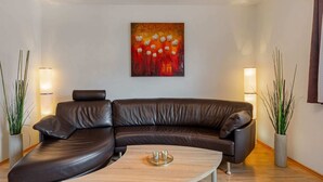 Ein modernes Wohnzimmer mit einer ledernen Eckcouch, einem Holztisch und zwei Stehlampen.