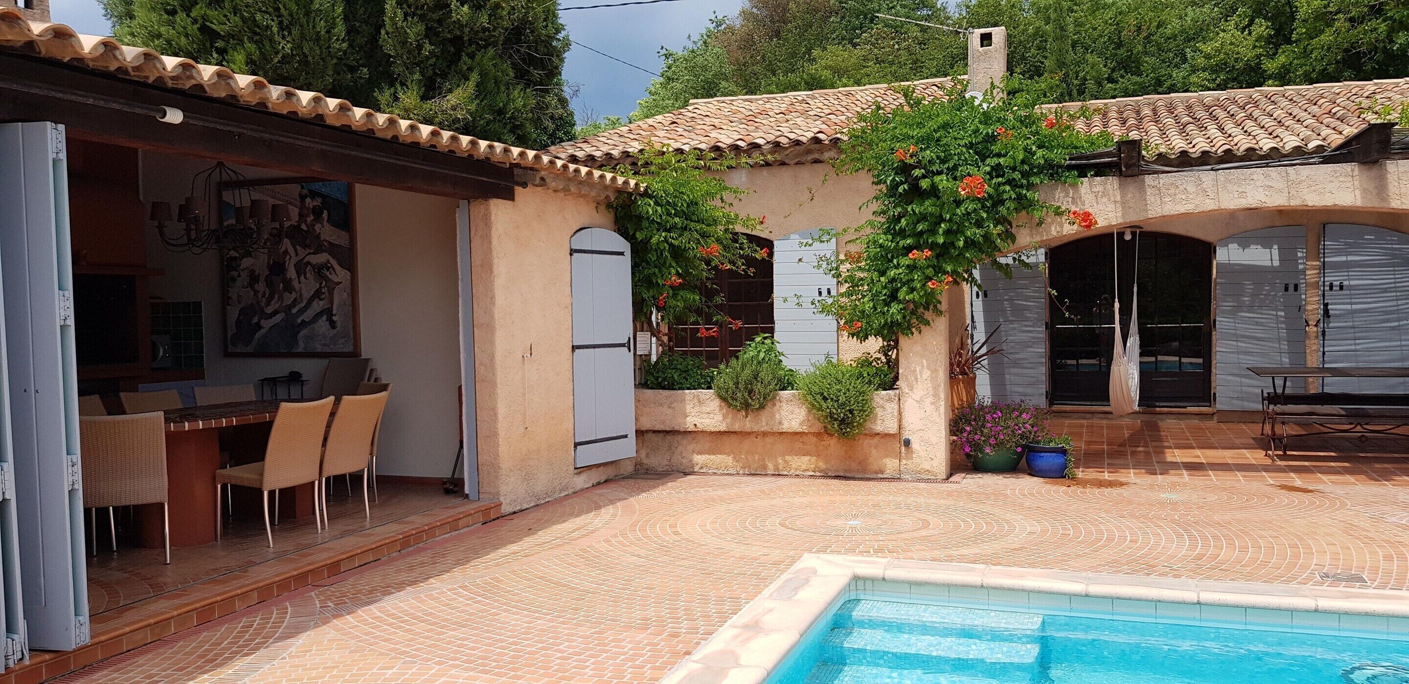 A poolside area with a dining set, a mural, and a covered patio.