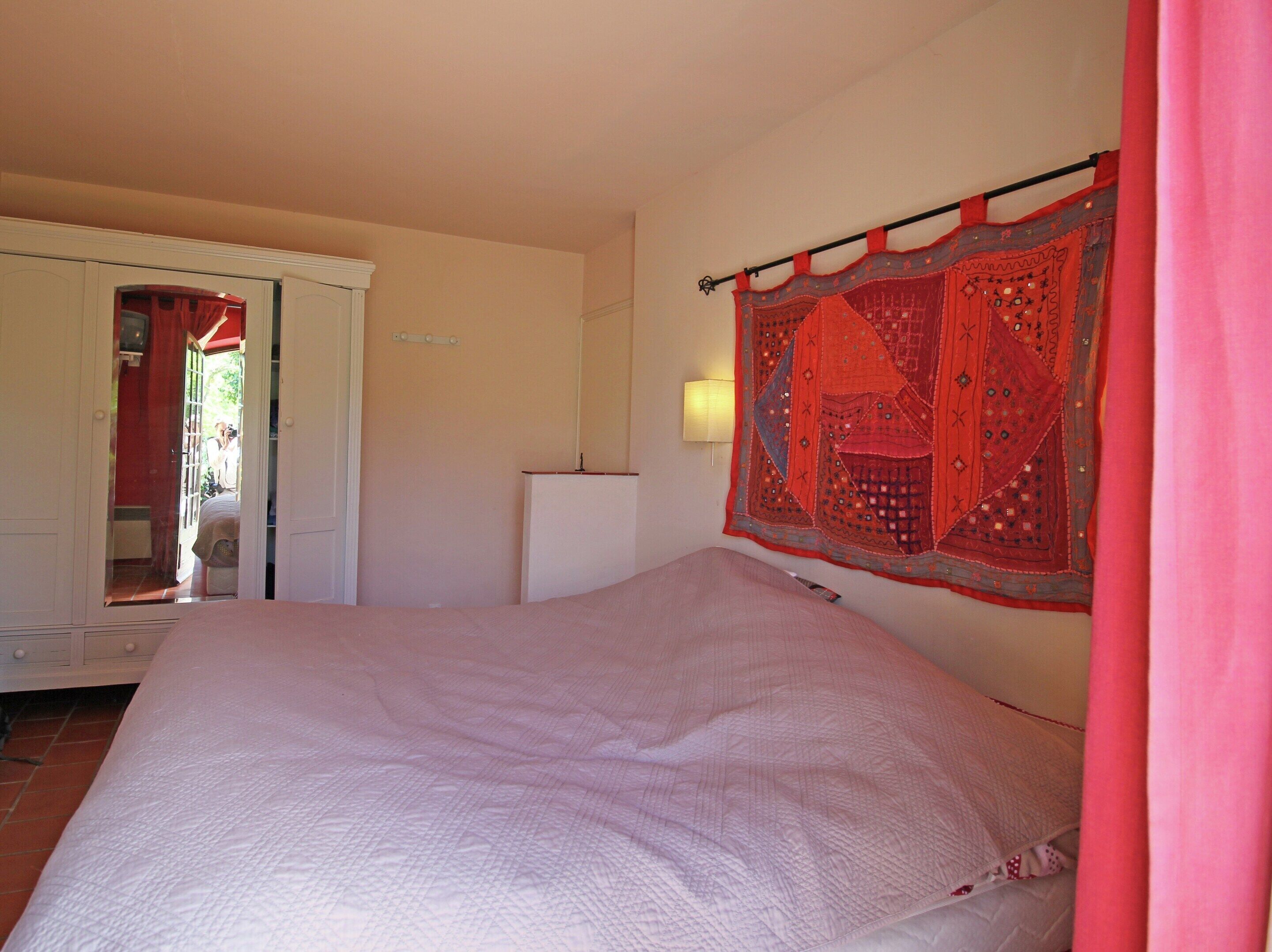 A bedroom with a bed, a wardrobe, and a wall-mounted lamp.