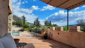 Eine Terrasse mit Pool, Gartenmöbeln und Blick auf die umliegende Landschaft.