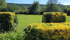 Ein gepflegter Garten mit ordentlich geschnittenen Hecken und freiem Blick auf die umliegende Landschaft.