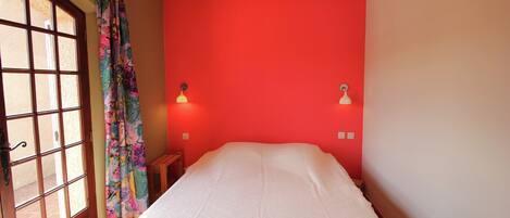 A room with a bed, a window with curtains, and two wall-mounted lights.