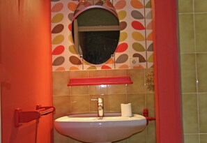 Een badkamer met een wastafel, spiegel en toiletrolhouder.