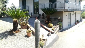 Ein zweistöckiges Gebäude mit Balkon, Blumentöpfen und einem Kakteengarten.
