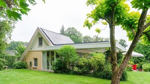 Une maison avec un toit en pente, une véranda et une pelouse bien entretenue.