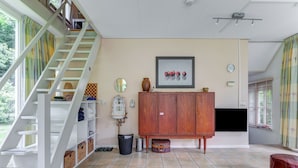 Un vaste espace de vie comprenant un escalier, une armoire en bois, un tableau encadré et un sol carrelé.