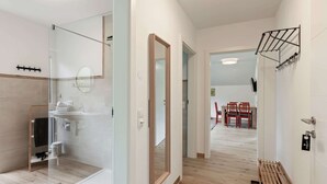 A modern bathroom with a glass shower enclosure, a wooden floor, and a mirror. - Apartment Salzburg Near Speiereck Lift (Sankt Michael im Lungau)