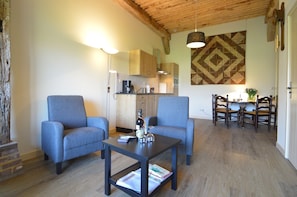A living room with two blue armchairs, a coffee table, and a dining area with a table and chairs.