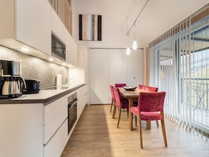 Ett modernt kök med en kaffebryggare, brödrost och diskho. Här finns också en matplats med ett bord och stolar, samt ett stort fönster med utsikt över omgivningarna.