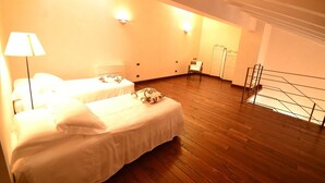 Une chambre d’hôtel avec deux lits, un plancher en bois et un escalier.