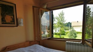 A bedroom with a bed, a window with an open shutter, a radiator, and a framed picture on the wall. - Enjoy the nature on Zlatibor (Zlatibor)