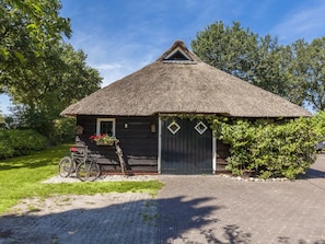 A thatched-roof building with a wooden door and windows, a bicycle, and a flower box. - Farmhouse in Balkbrug With Sauna (Balkbrug)