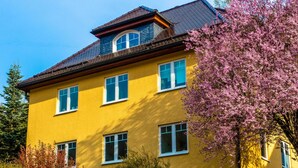 A yellow building with multiple windows and a sloped roof. - Ferienwohnung mit Sauna in Schonbrunn Thuringen (Schleusegrund)