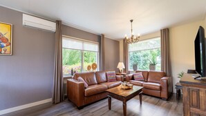 A living room with a sectional sofa, a wooden coffee table, and a television. - Cozy Holiday Home in Nistelrode With Garden (Nistelrode)