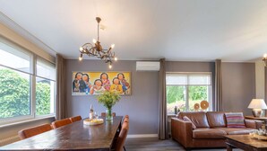 A spacious living area with a dining table, leather sofa, and a chandelier. - Cozy Holiday Home in Nistelrode With Garden (Nistelrode)