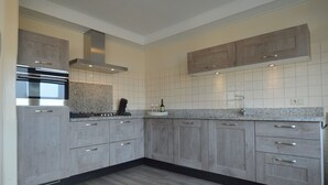 A modern kitchen with grey cabinets, a stainless steel oven, and a granite countertop. - Cozy Holiday Home in Nistelrode With Garden (Nistelrode)