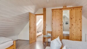 Quarto com móveis de madeira, uma cama, uma cadeira e um guarda-roupa.