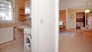 A modern apartment with a laundry area, a kitchen, and a dining area. - Mountain View Apartment in Going am Wilden Kaiser near Ski Area (Going am Wilden Kaiser)