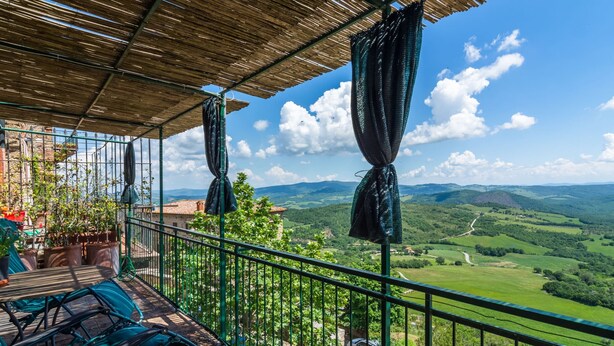 Ein Balkon mit Blick auf sanfte Hügel und einen klaren Himmel.