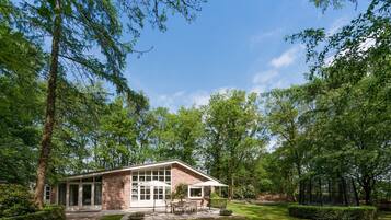 A modern house with a patio, surrounded by lush greenery and trees.
