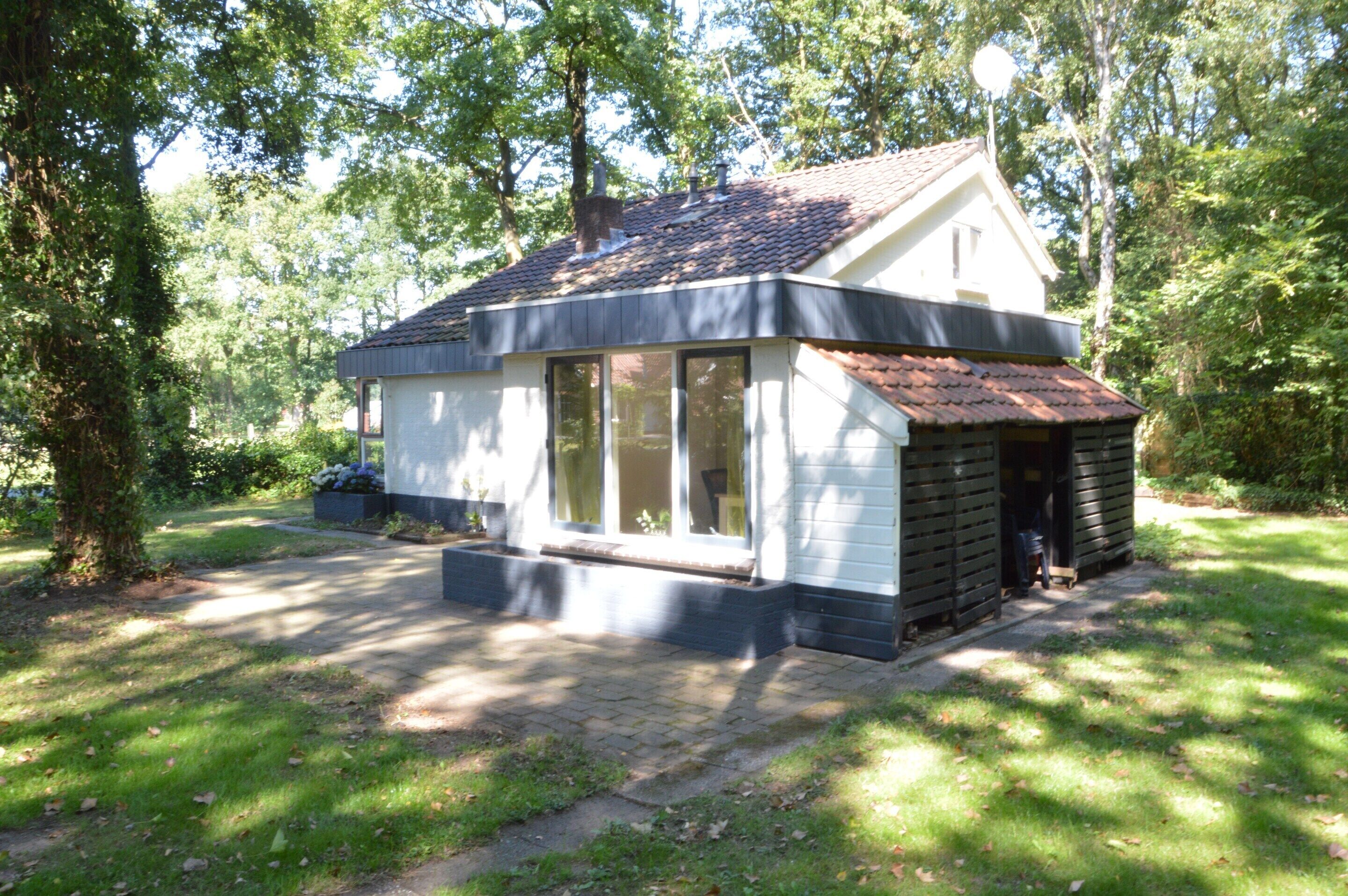 Ein kleines, eingeschossiges Haus mit geneigtem Dach, großen Fenstern und einer Veranda.
