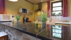 A kitchen with granite countertops, a microwave, a coffee maker, and potted plants. - Cozy Family Stay in Durbuy (Durbuy)
