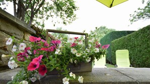 A stone ledge with a wooden planter filled with pink and white flowers. - Cozy Family Stay in Durbuy (Durbuy)