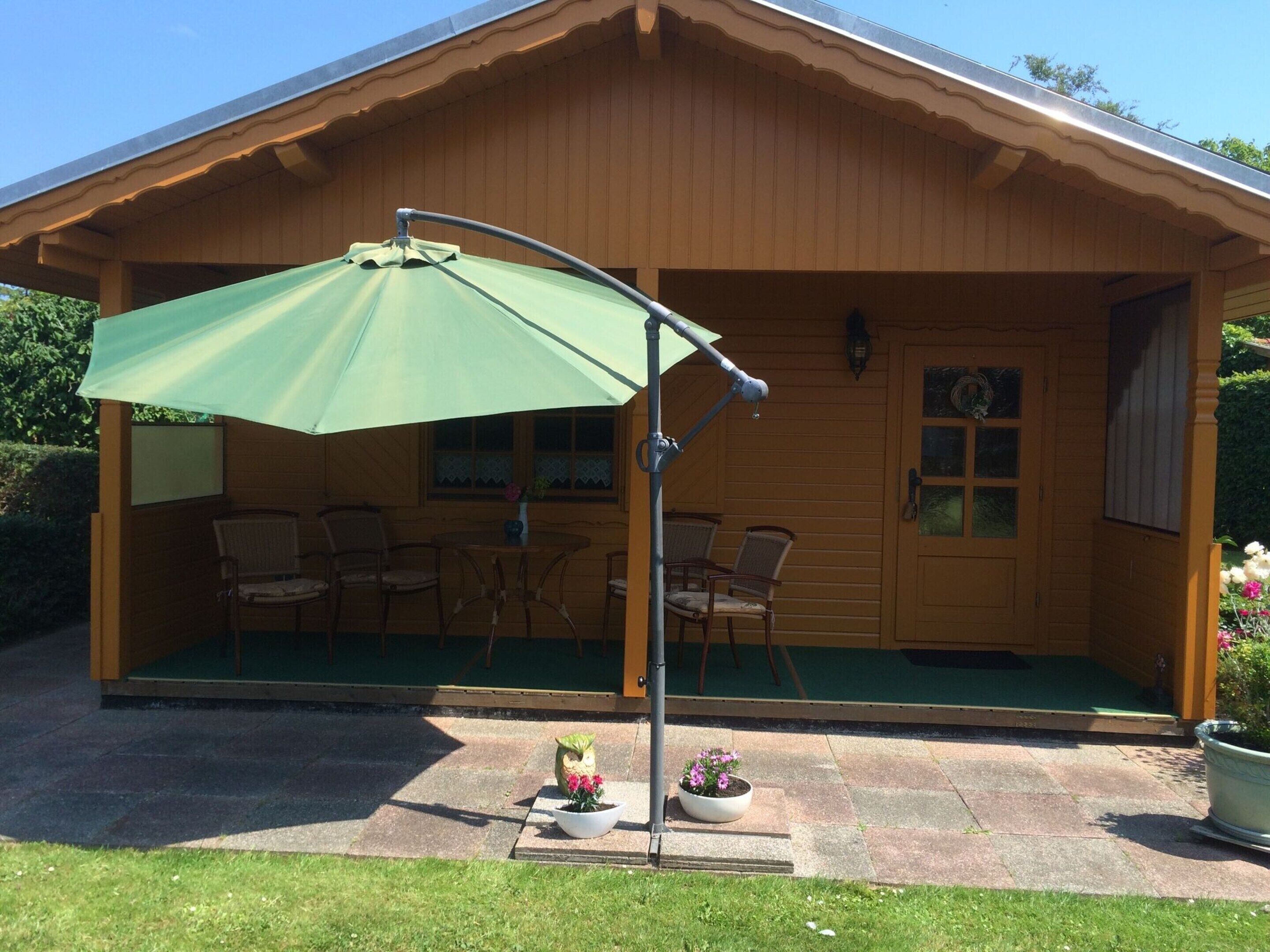 A wooden cabin with a covered patio, outdoor seating, and potted plants.