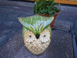 A ceramic owl-shaped planter with a green and beige color scheme, placed on a stone surface outdoors. - Log Cabin Near Baltic Sea Lighthouse (Bastorf)