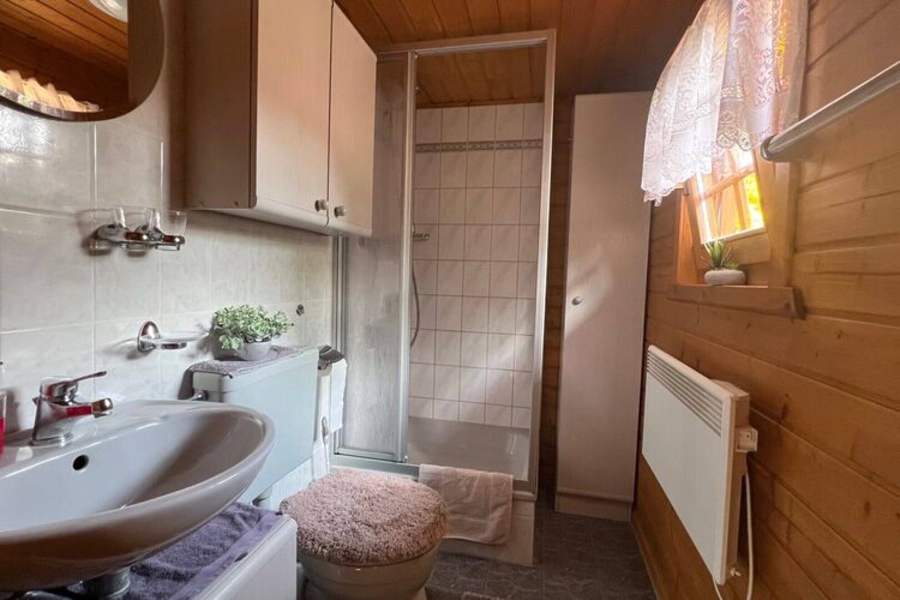 A compact bathroom with a sink, toilet, and shower.