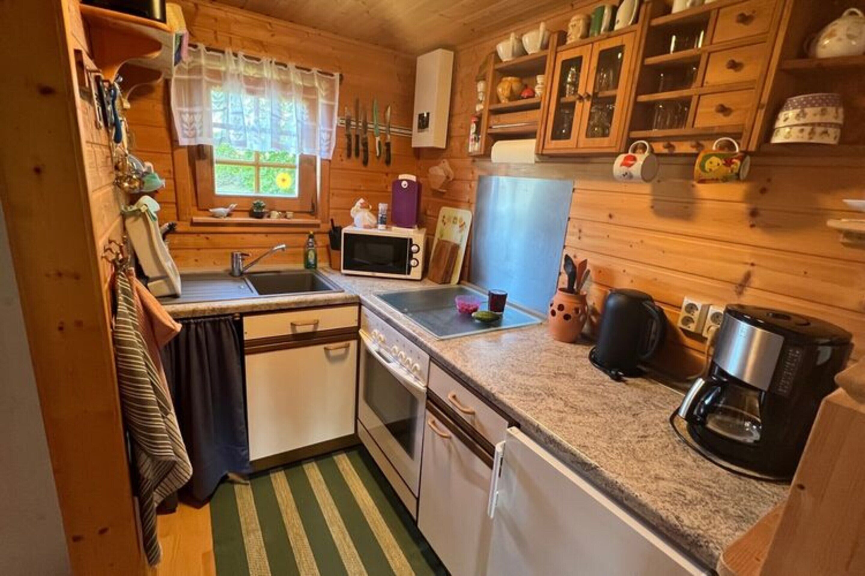 Une cuisine compacte avec des meubles en bois, un four à micro-ondes, une machine à café et un évier.