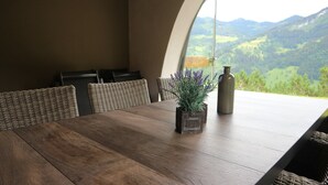 Een eettafel met rieten stoelen, een vaas met lavendel en een fles.