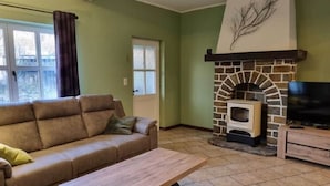 A living room with a stone fireplace, a sofa, a coffee table, and a television.