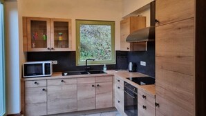 A compact kitchen with wooden cabinets, a microwave, a sink, and a stove.