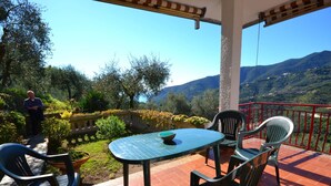 Une terrasse avec une table et des chaises, un mur en pierre et une vue sur un paysage montagneux.