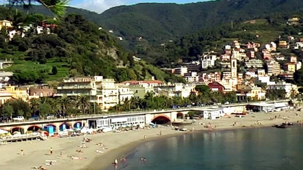 Une ville côtière avec une plage, un pont et des bâtiments situés sur une colline.