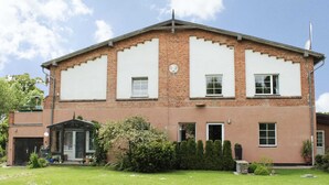 A two-story building with a brick facade, large windows, and a well-maintained lawn. - Ferienwohnung Gerda in Ostseenahe (Wittenbeck)