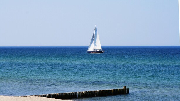 A sailboat on calm waters with a clear sky. - Ferienwohnung Gerda in Ostseenahe (Wittenbeck)